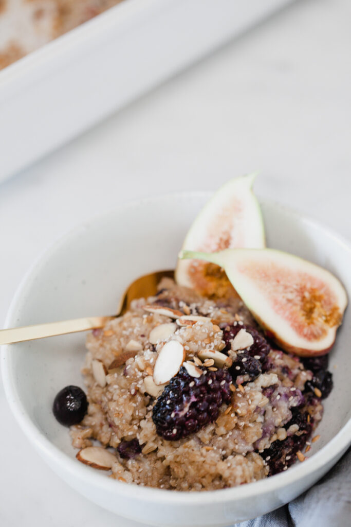 Baked Steel Cut Oatmeal topped with berries and nuts in a white bowl